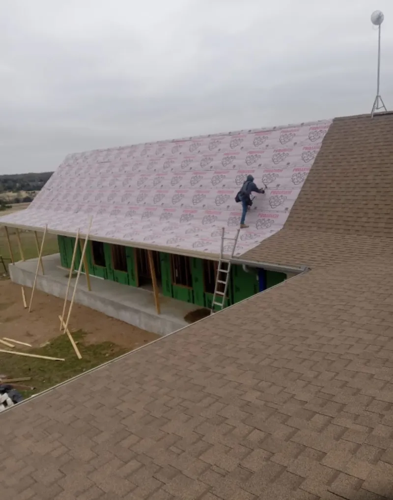 Worker preparing underlayment for a metal roof installation in Bellevue